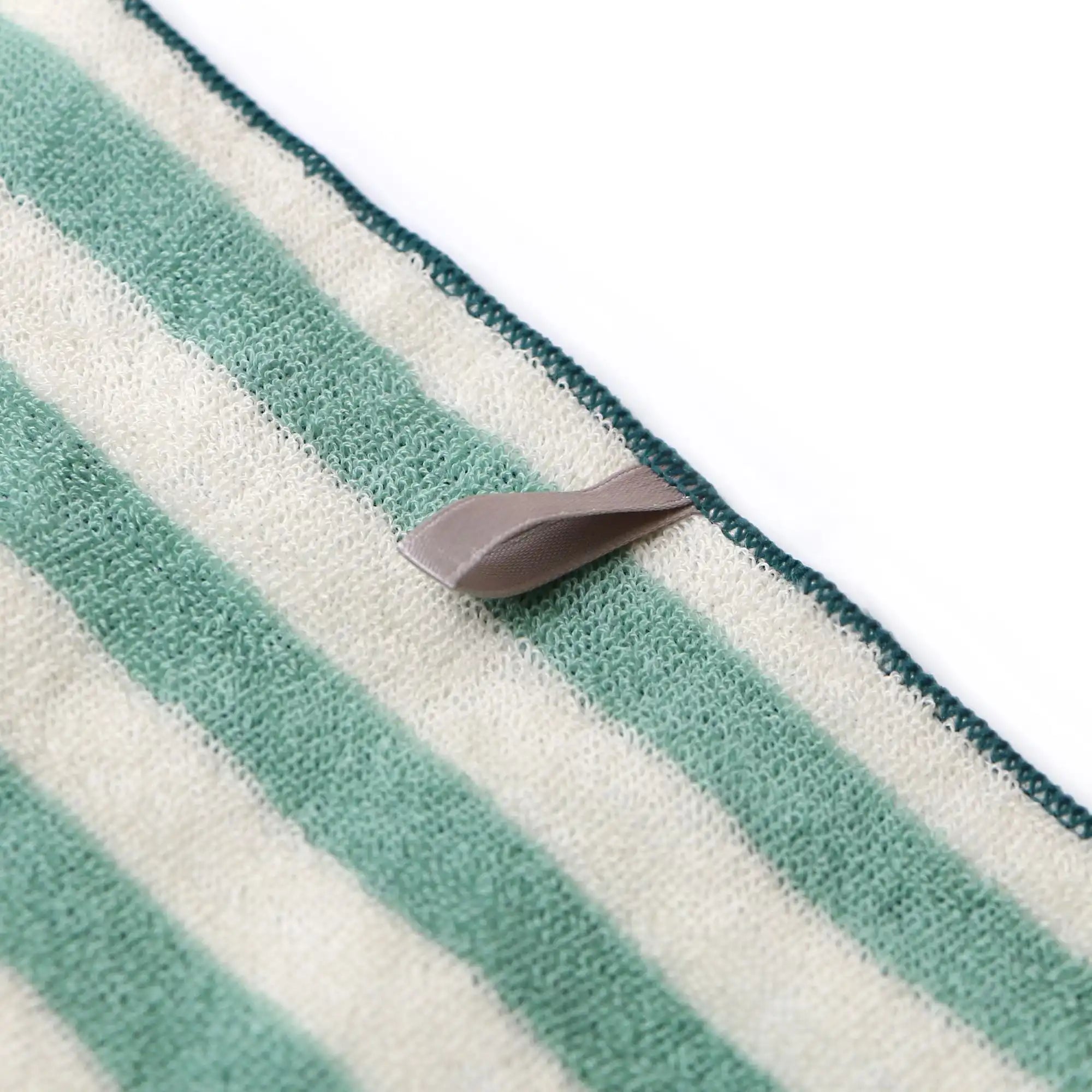 Striped green and white Imabari towel with a brown tug pad on a white background