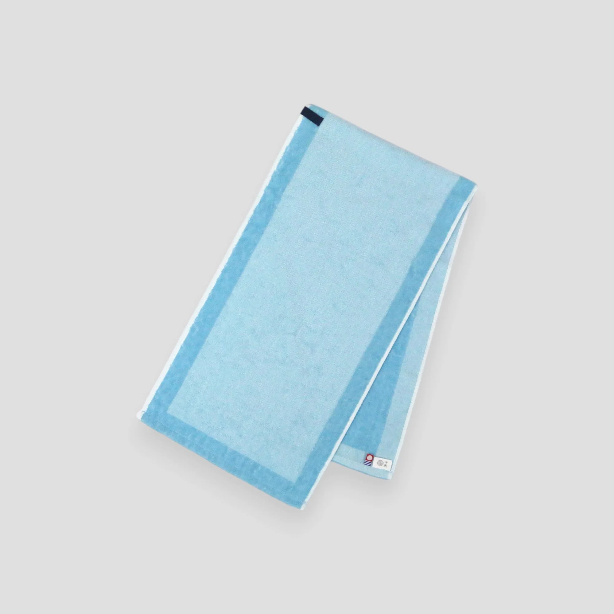 A folded blue Imabari towel, showing the brand label and a hanging loop