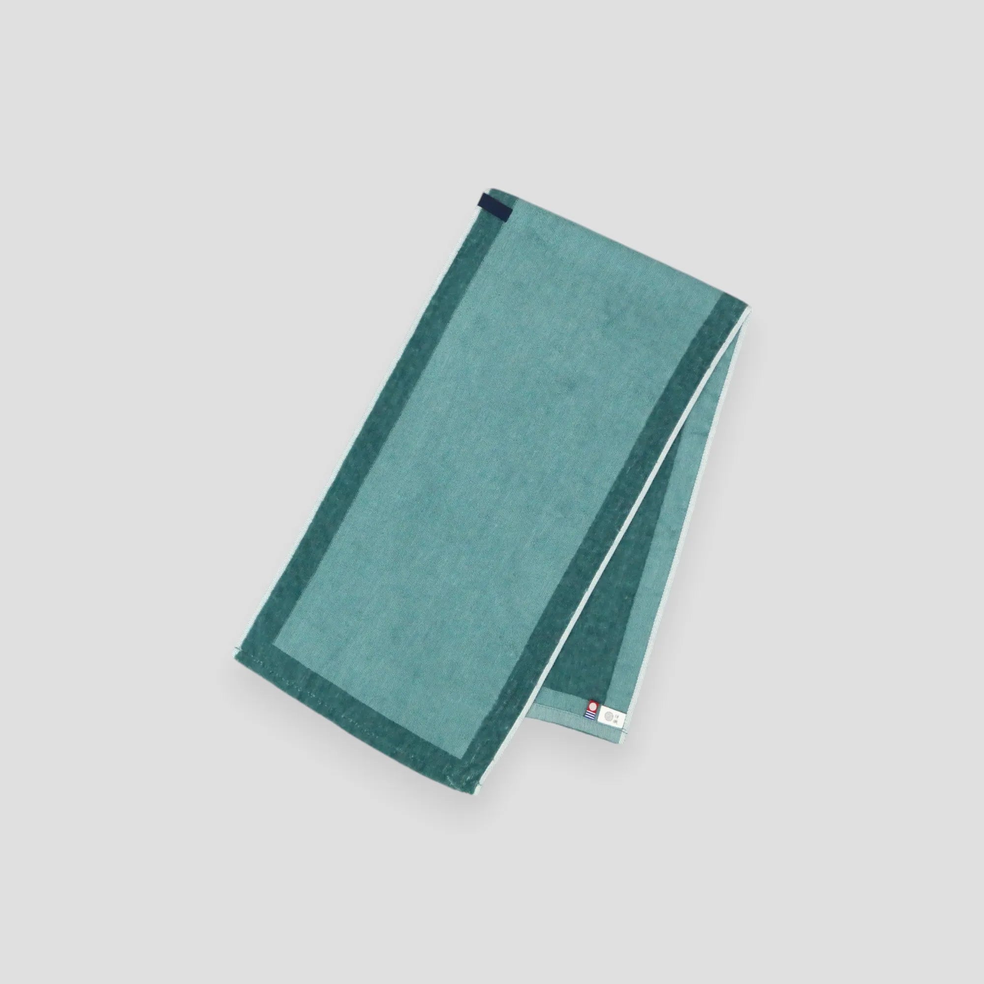 A folded green Imabari towel, showing the brand label and a hanging loop