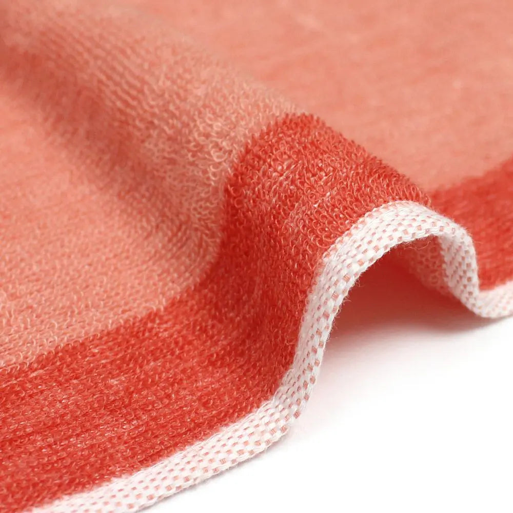 A close-up of the texture and side of a reversible orange Imabari towel