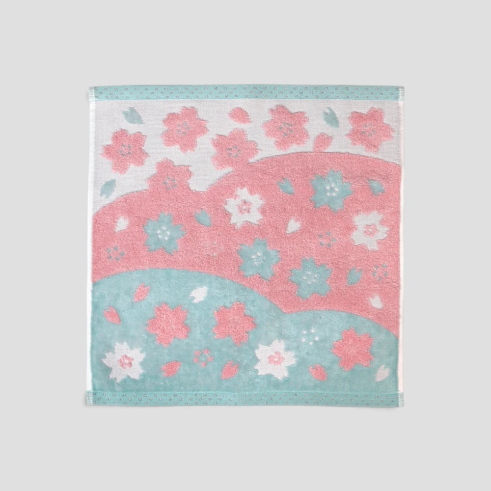 A square cotton Imabari wash towel with a pink and blue cherry blossom pattern, displayed flat against a neutral light gray background.