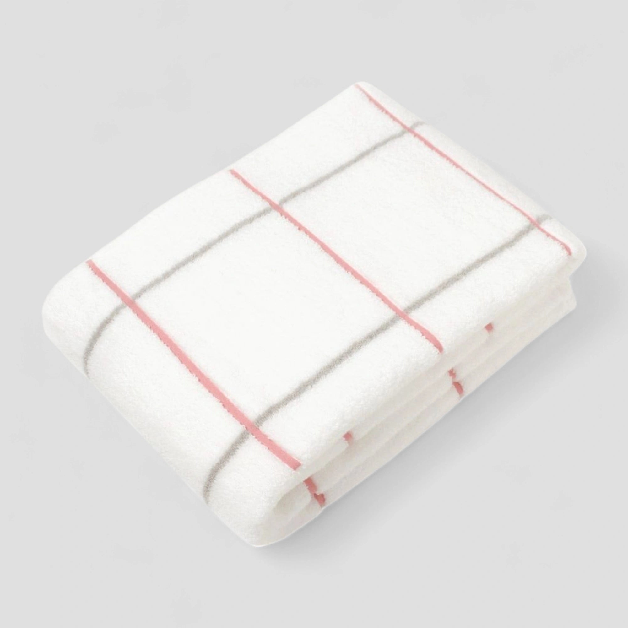 Folded white Imabari towel with pink stripes on a light gray background