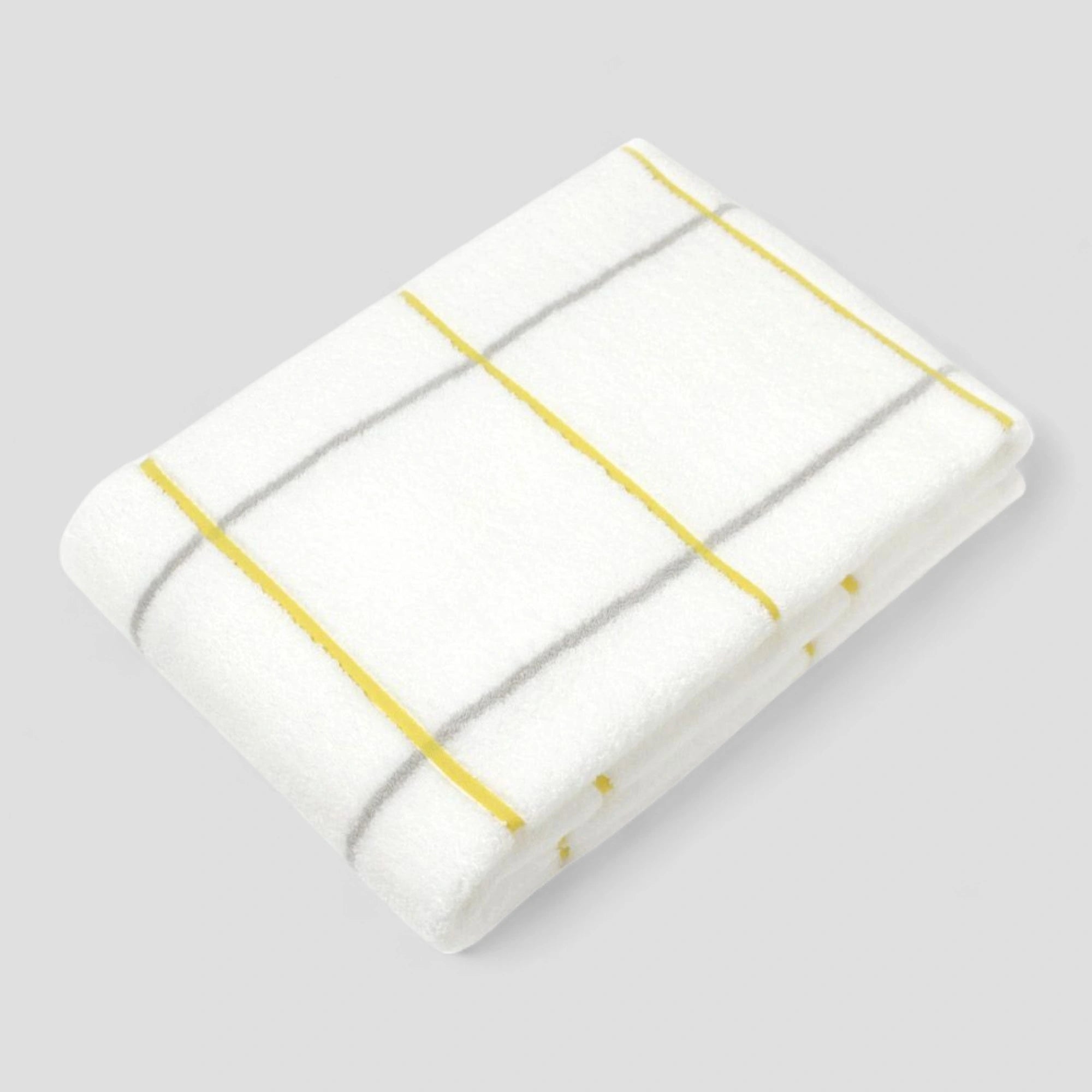 Folded white Imabari towel with yellow stripes on a light gray background