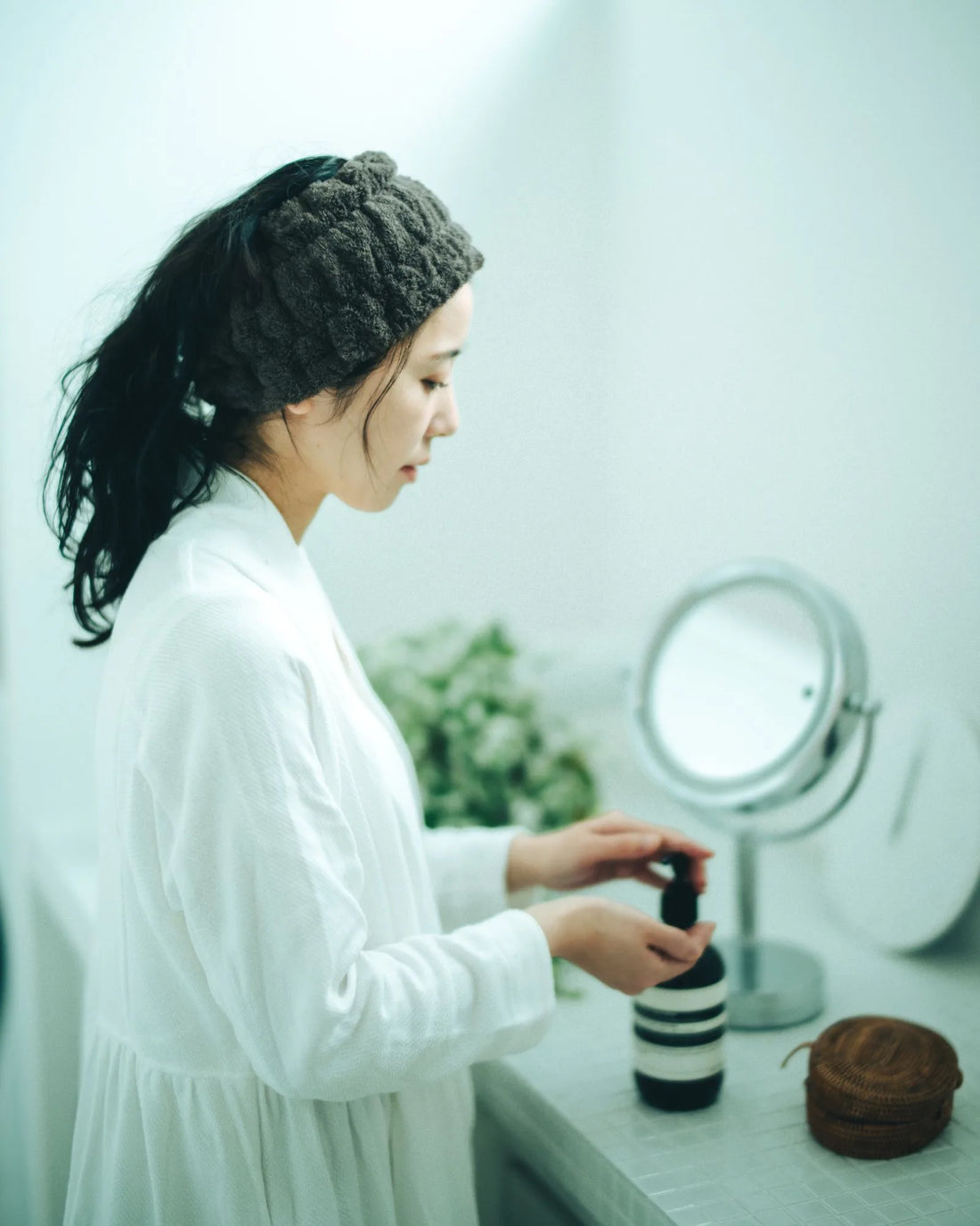 Woman applying makeup in front of a mirror with wearing Imabari towel head band 