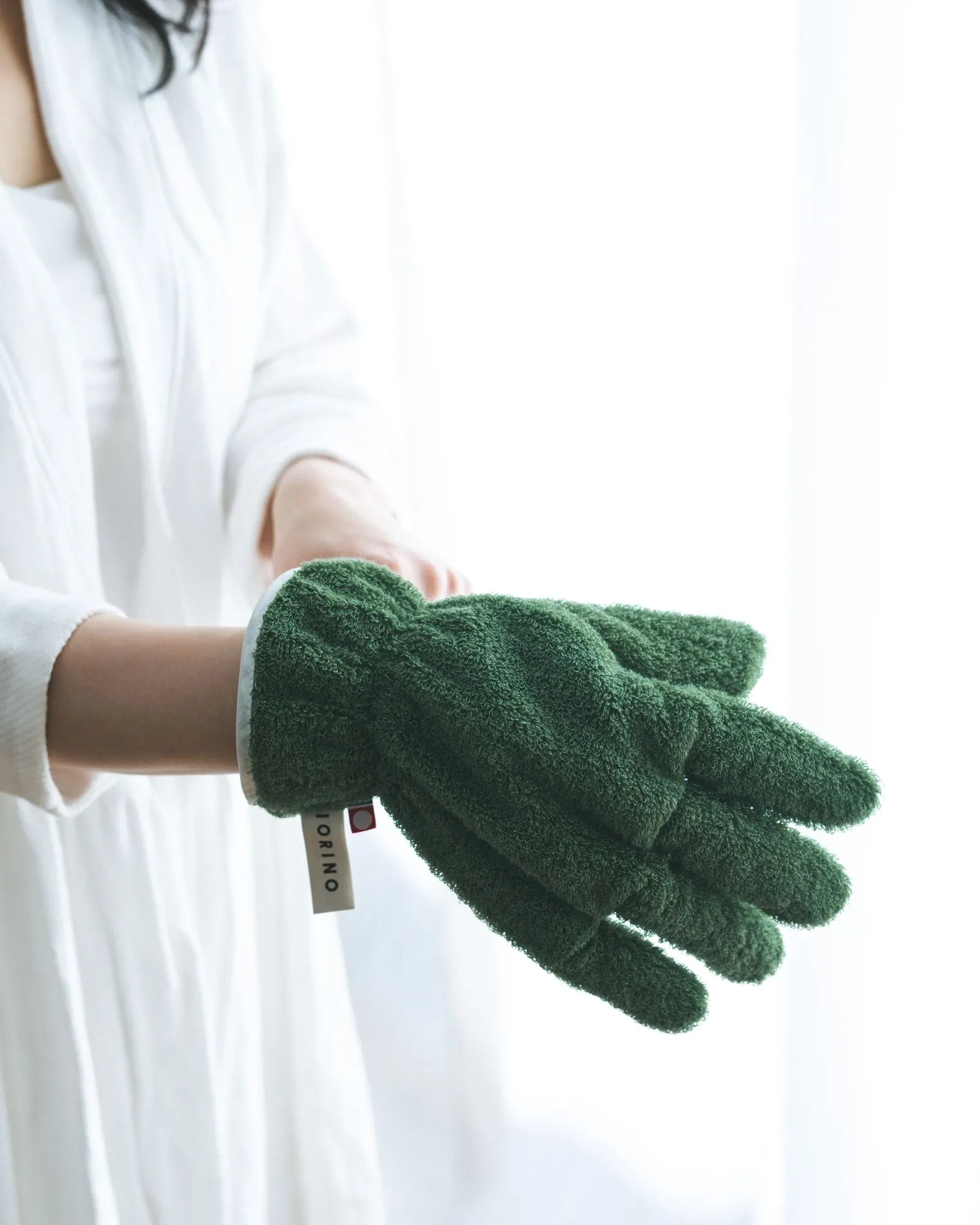 Green Imabari towel gloves held by a person against a white background