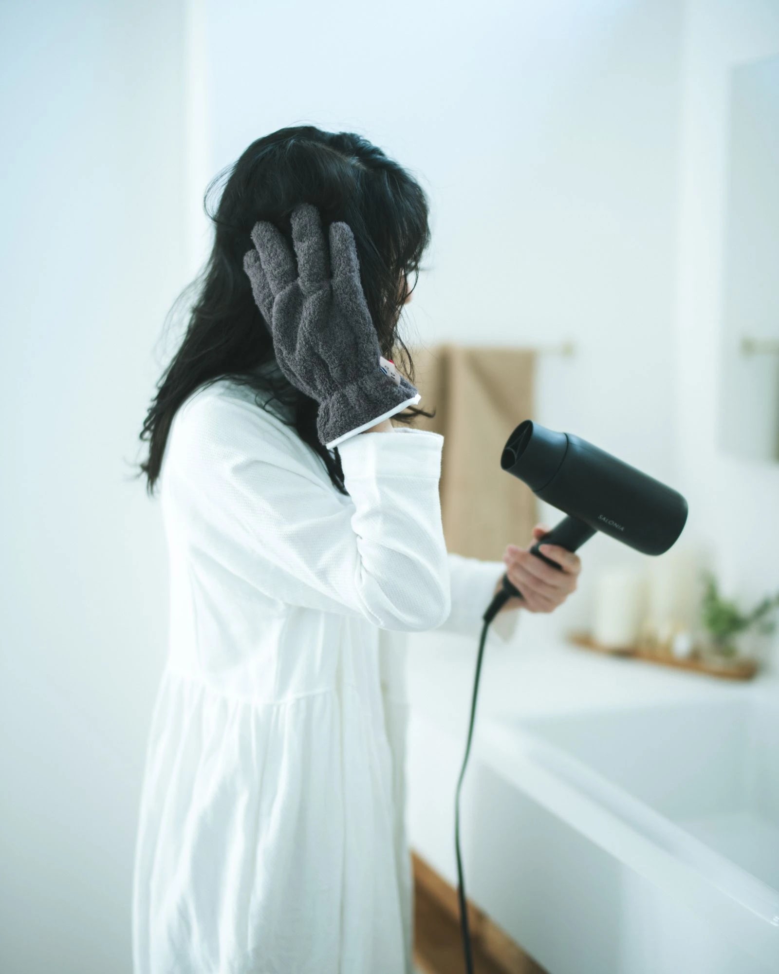 Person using a hair dryer with a Imabari  towel drying glove in a bathroom setting