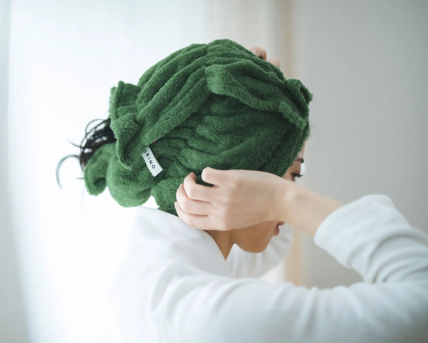 Person wearing a green Imabari towel on their head with a blurred background