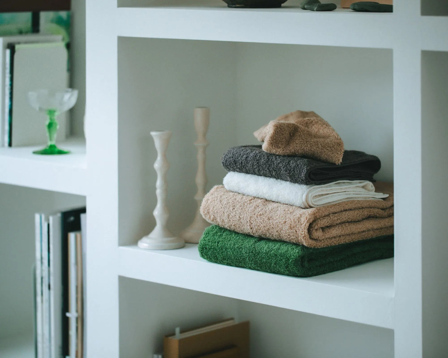 Stack of folded Imabari towels on a white shelf with decorative items.