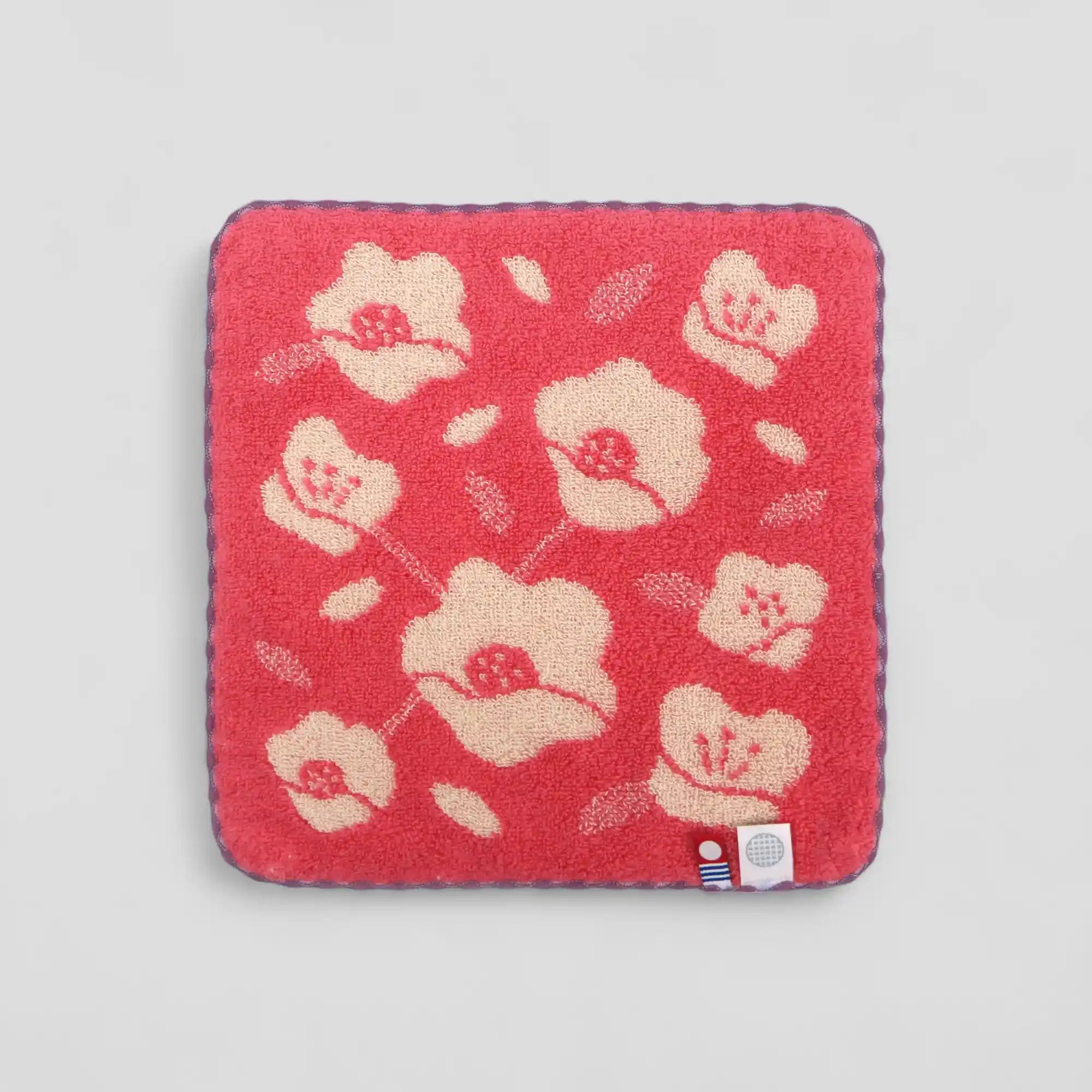 Red Imabari towel with beige floral pattern and labels of Iambari towel brand mark and IORI&
