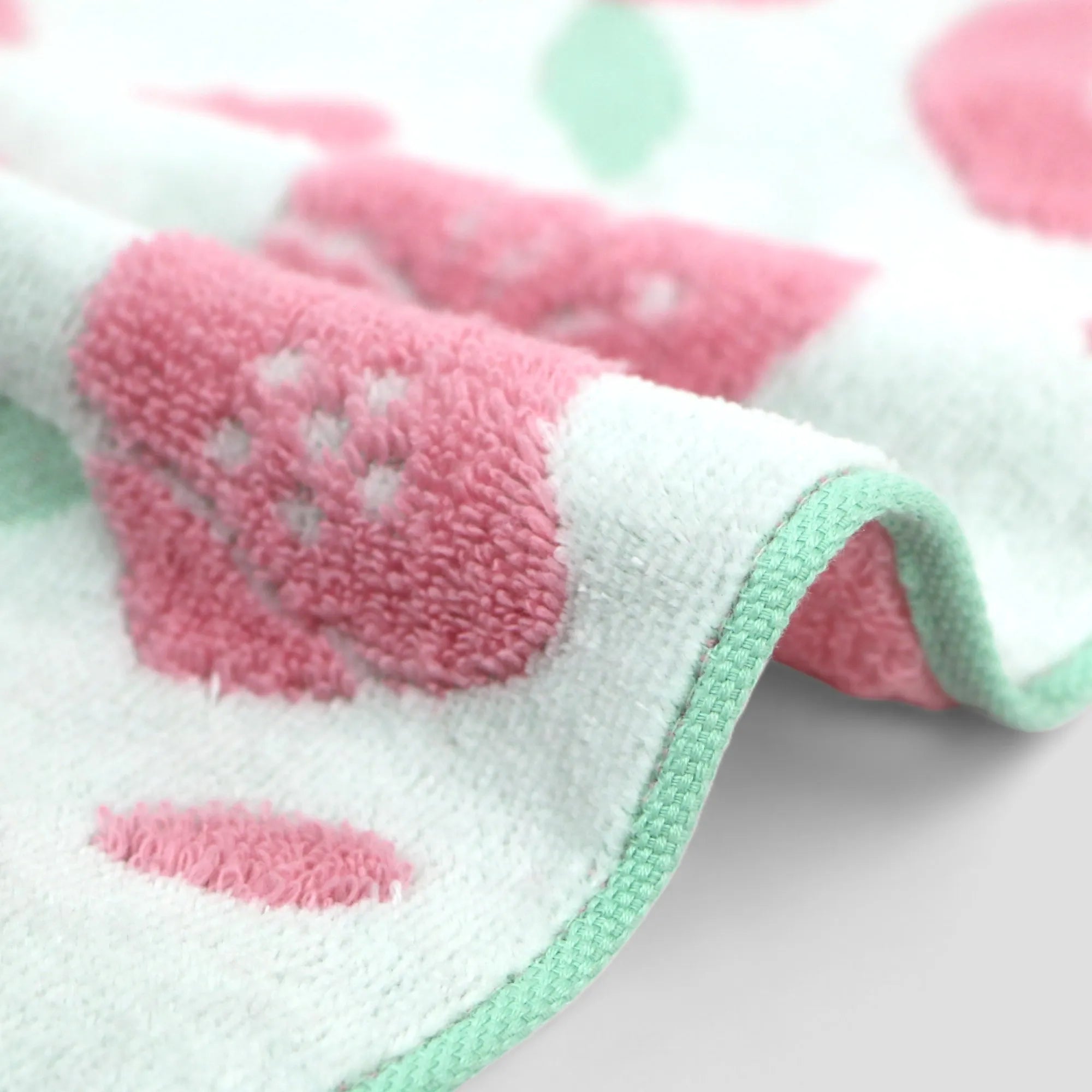 Close-up of a edge of pink floral Imabari towel on a light-gray background