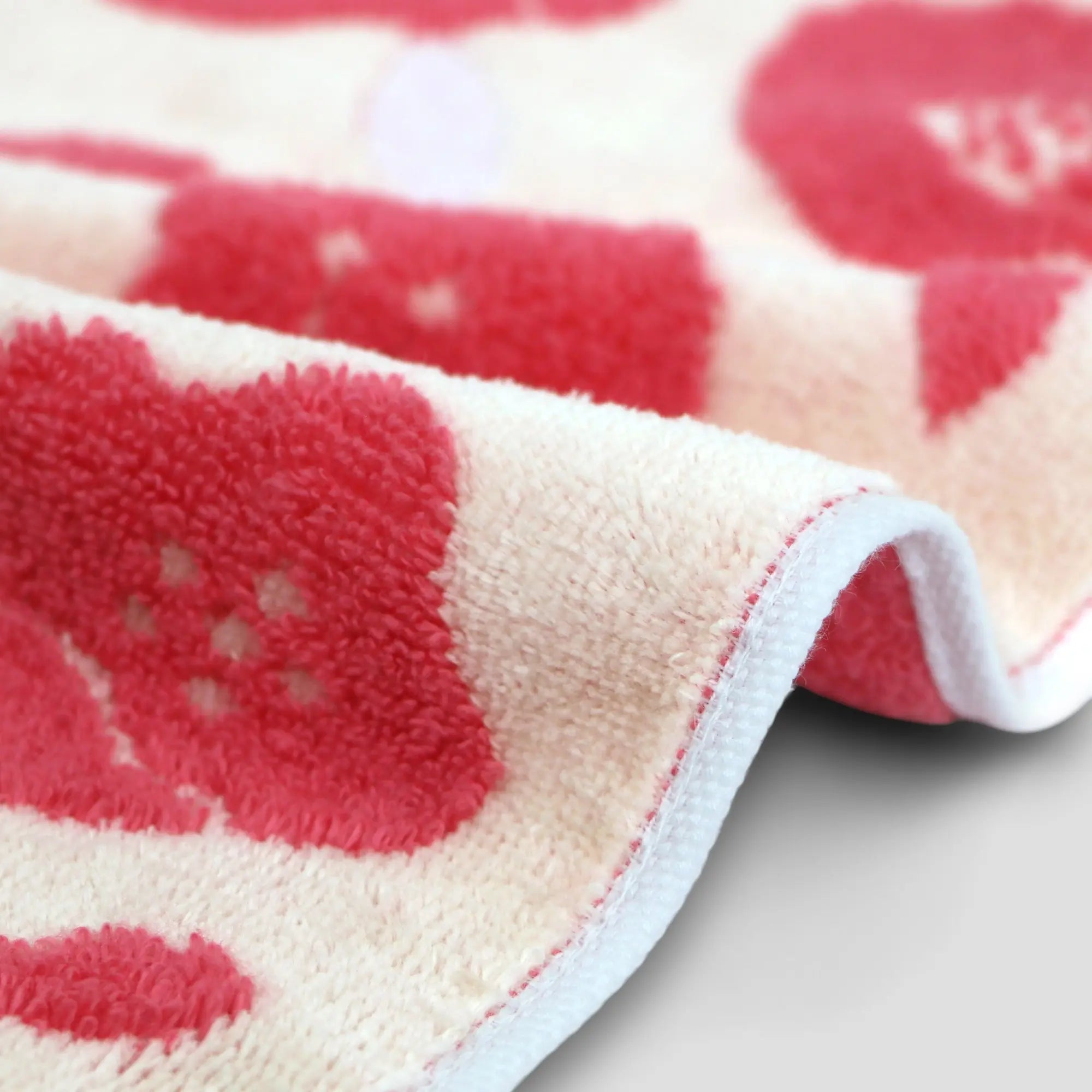 Close-up of a edge of red floral Imabari towel on a light-gray background