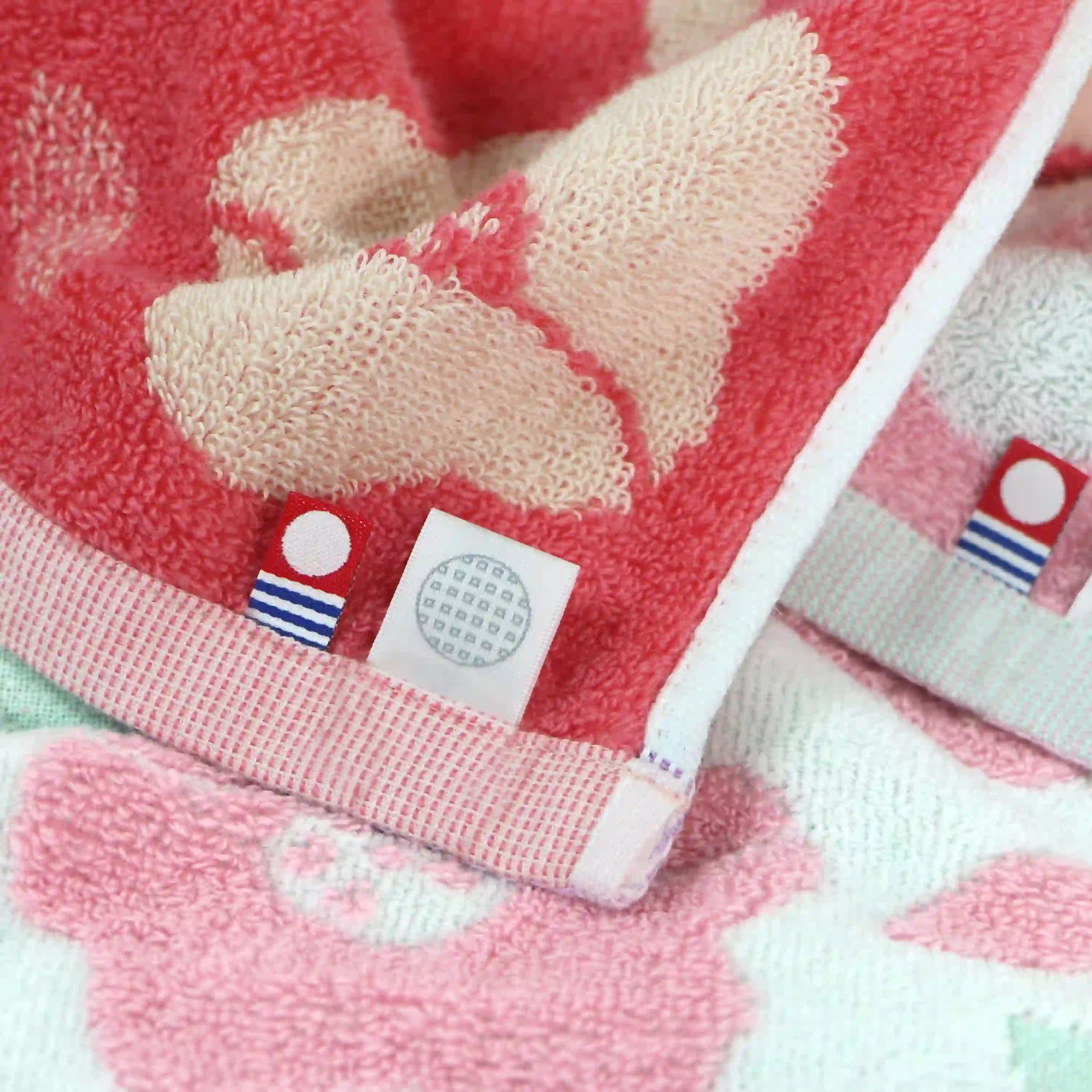 Close-up of a red Imabari towel with a floral  design and a visible brand label.