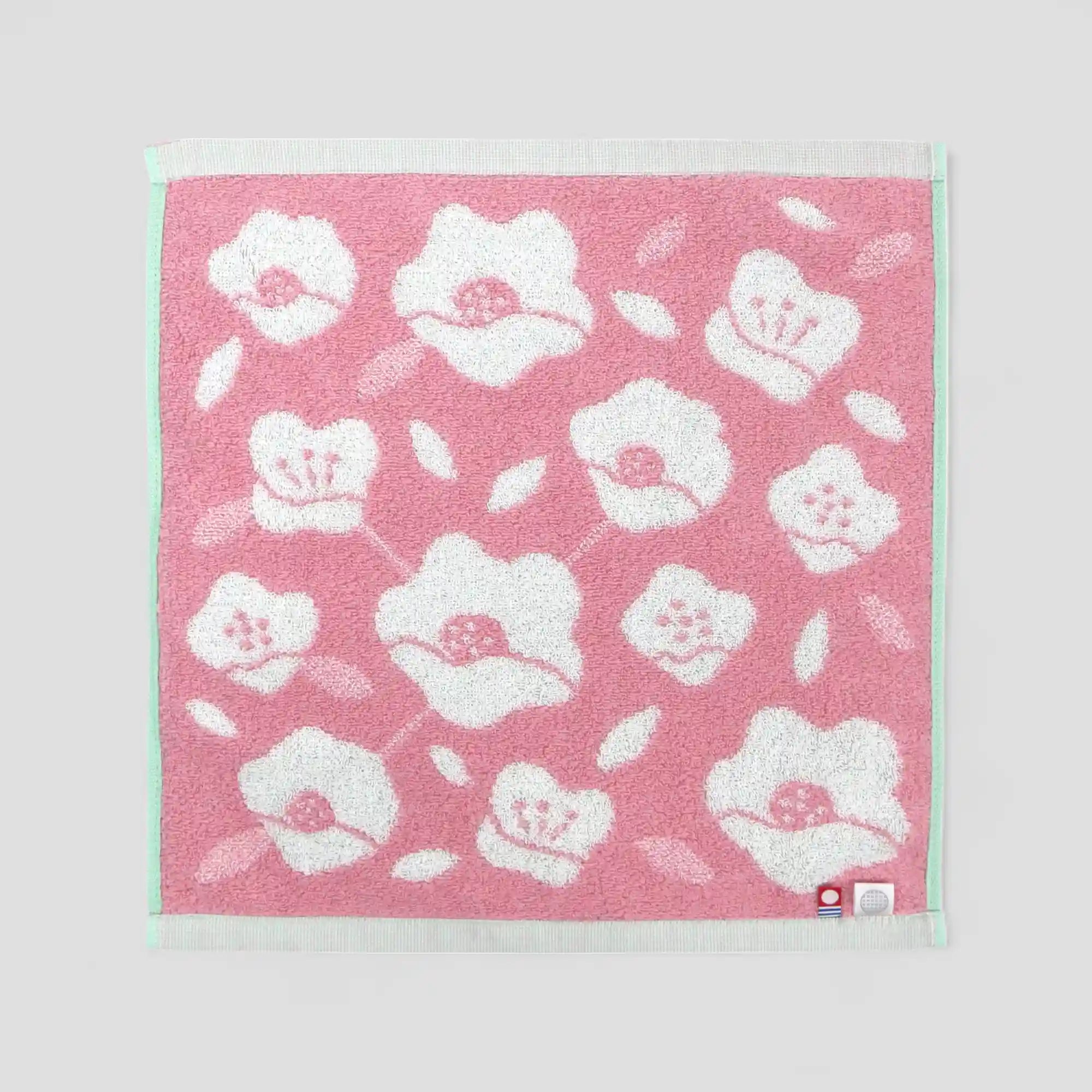 White floral patterned pink  Imabari towel with showing labels of Imabari towel brand mark and IORI&