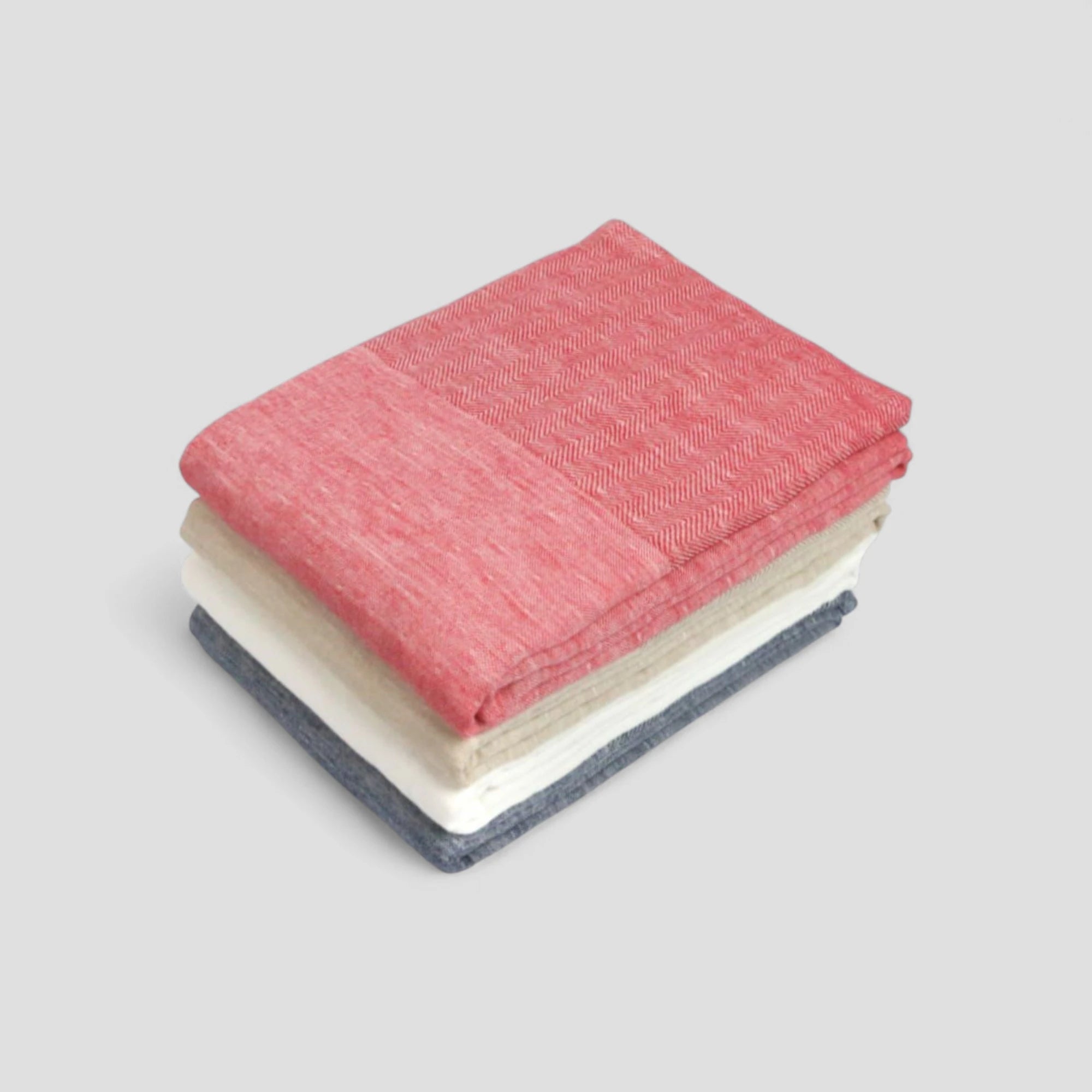 Stack of folded Imabari towel in red, beige, and gray on a light gray background