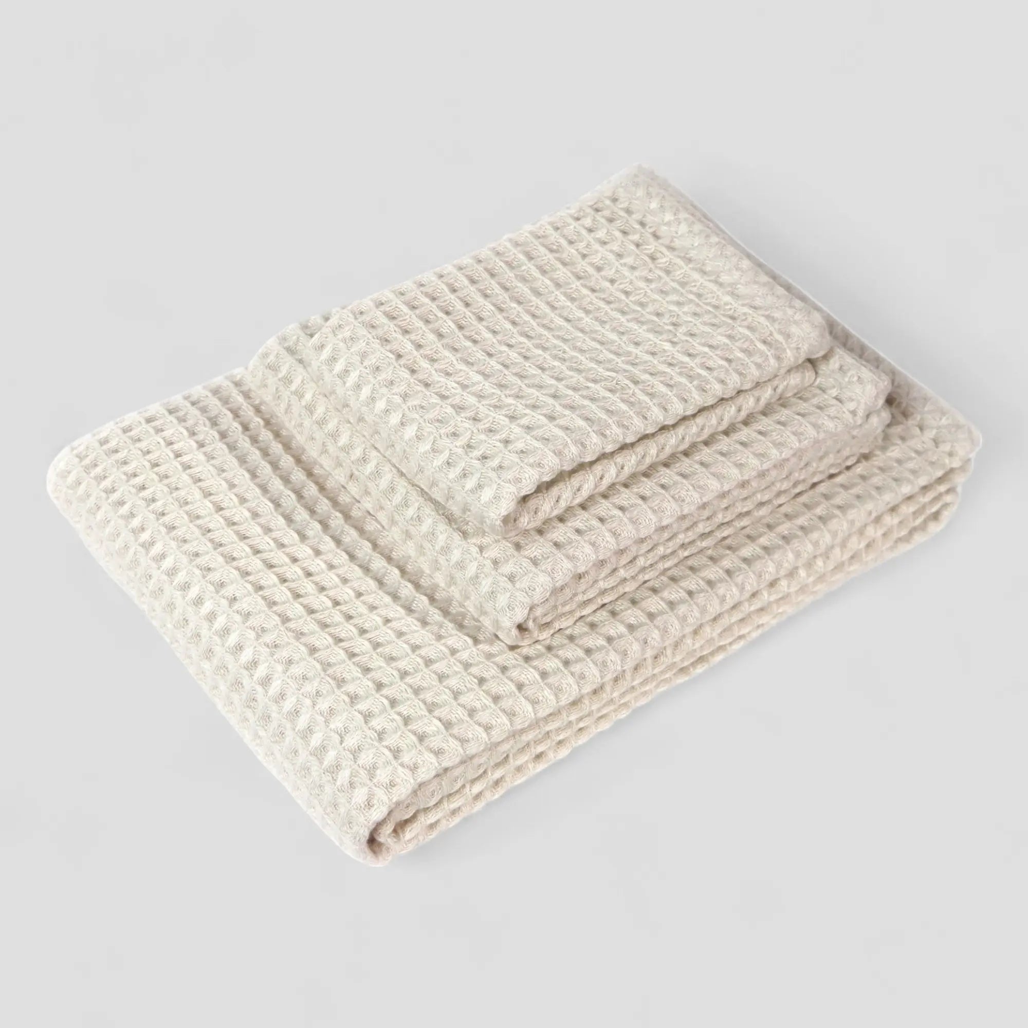 Folded 3 sets of off-white waffle towel on a light gray background