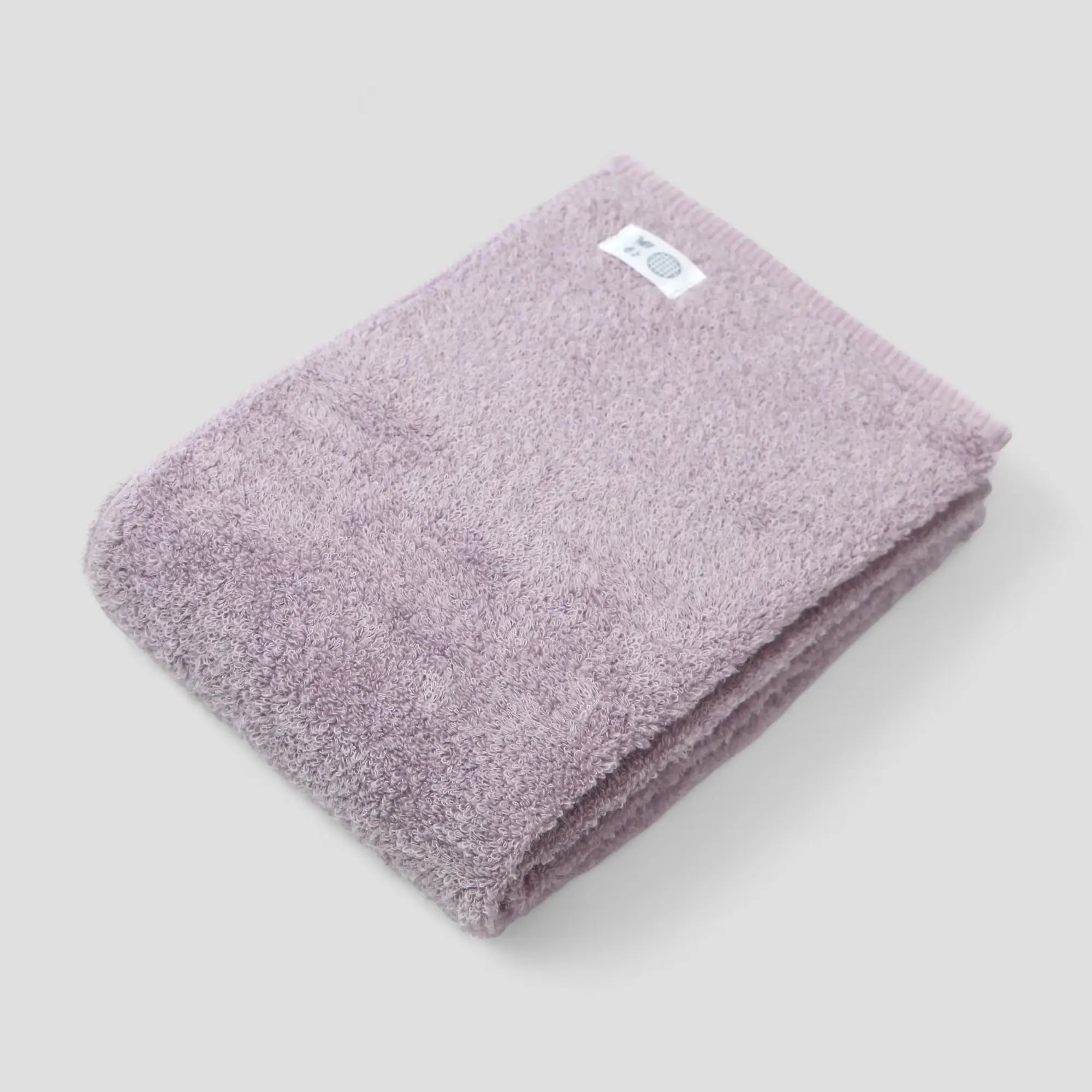 Folded purple Imabari towel with a brand label on a light gray background