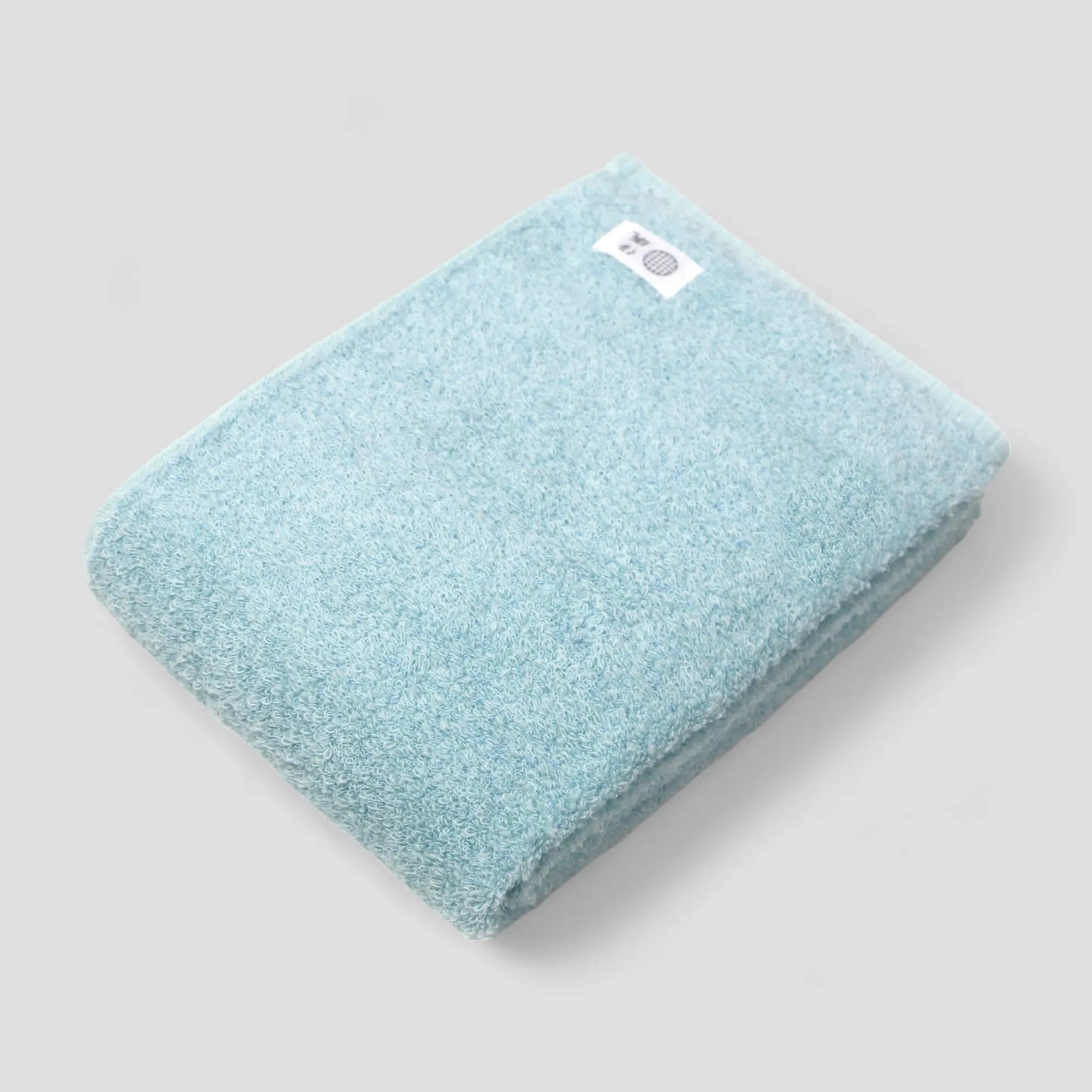 Light blue Imabari towel with a brand label on a gray background