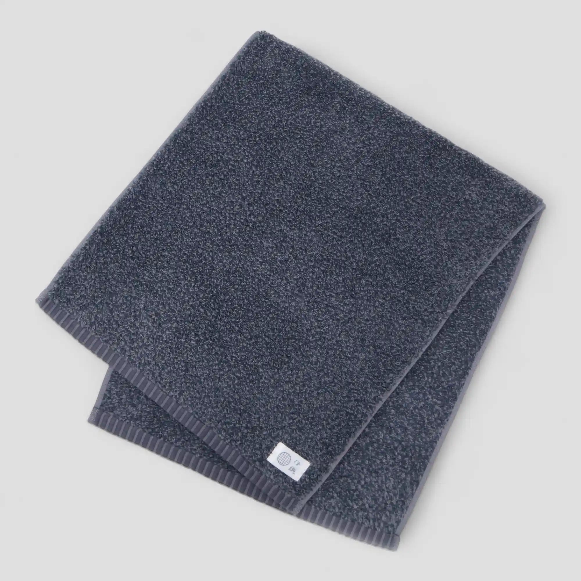 Folded dark gray Imabari towel on a light gray background