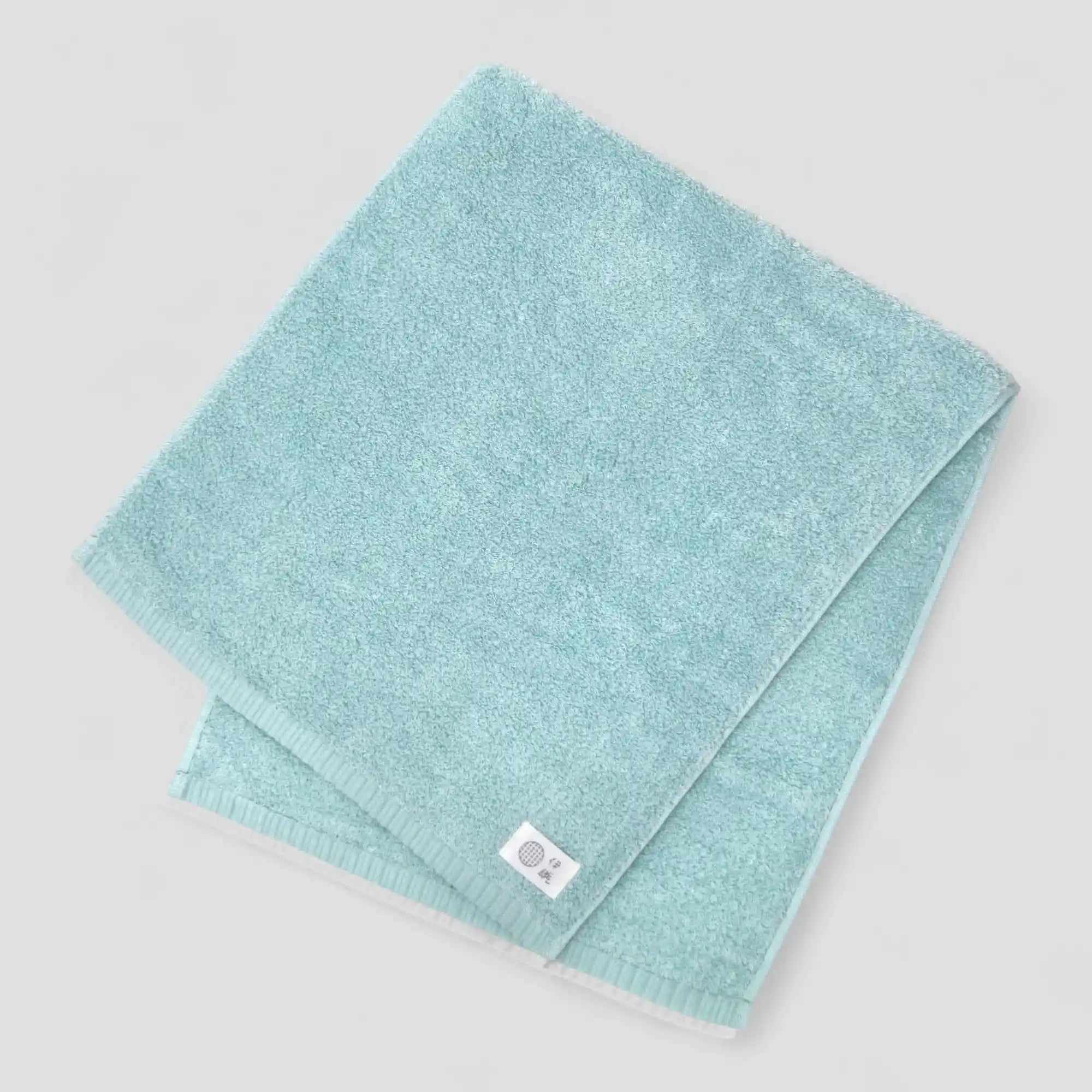 Folded light blue Imabari towel with a brand label on a gray background