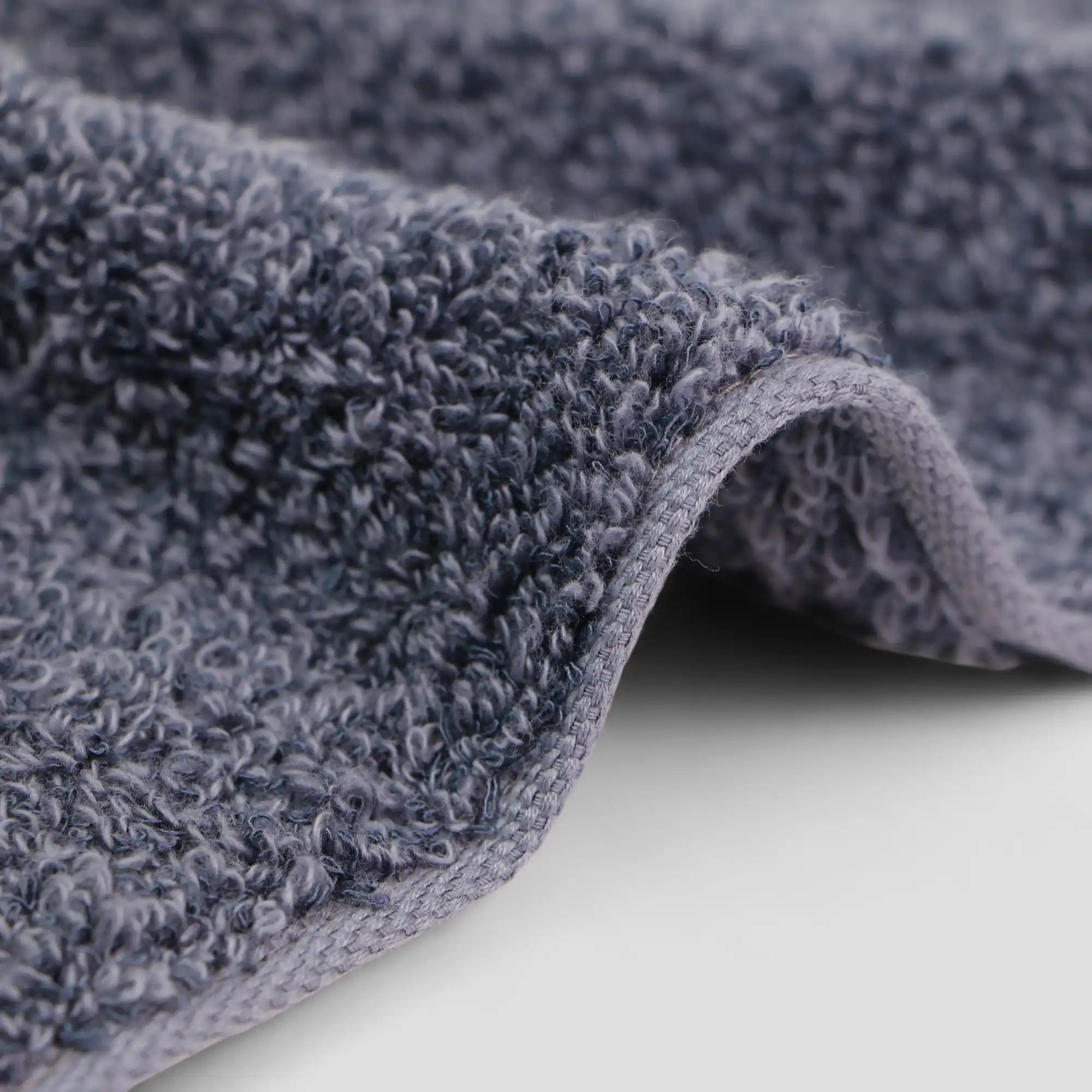 Close-up of a textured ink-blue Imabari towel fabric on a light gray background