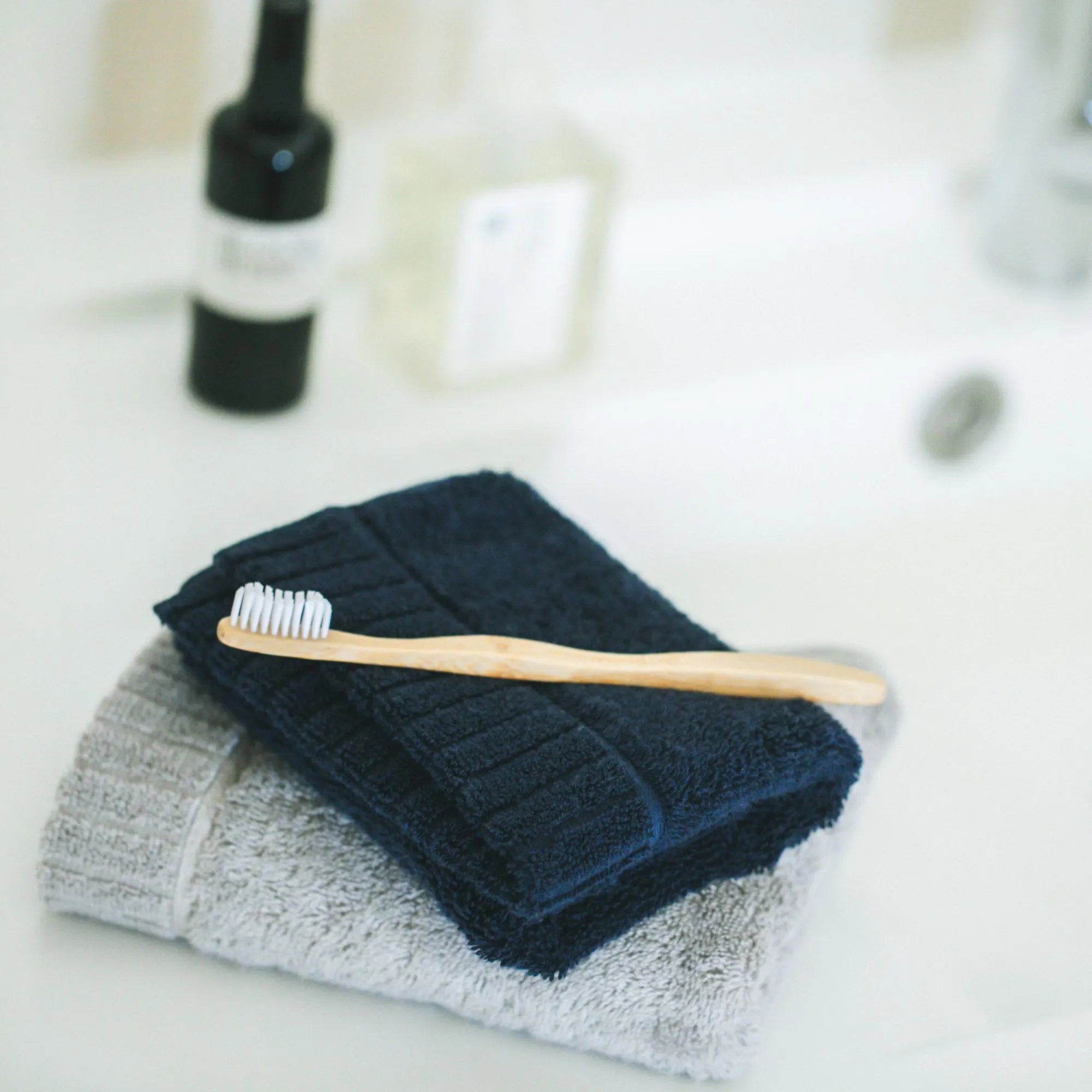 Bamboo toothbrush on a stack of folded Imabari towels with a blurred background