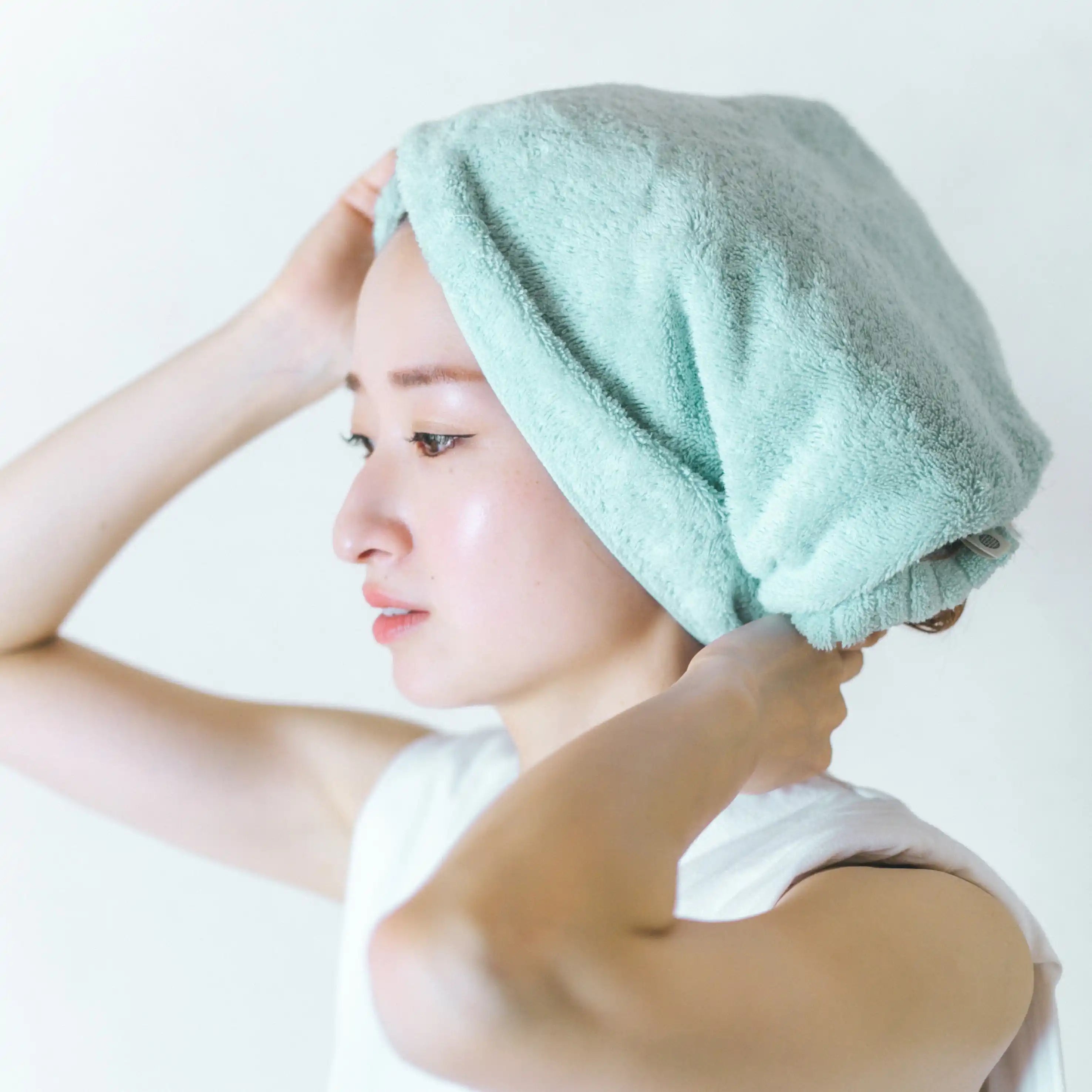 Woman with a blue Imabari towel on her head against a white background