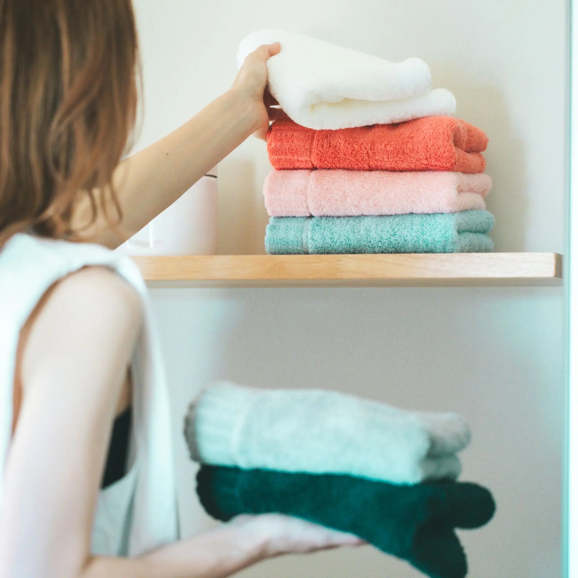 Person arranging colorful Imabari towels on a shelf