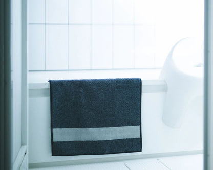 Navy Imabari towel bath mat on a white bathtub with tiled wall