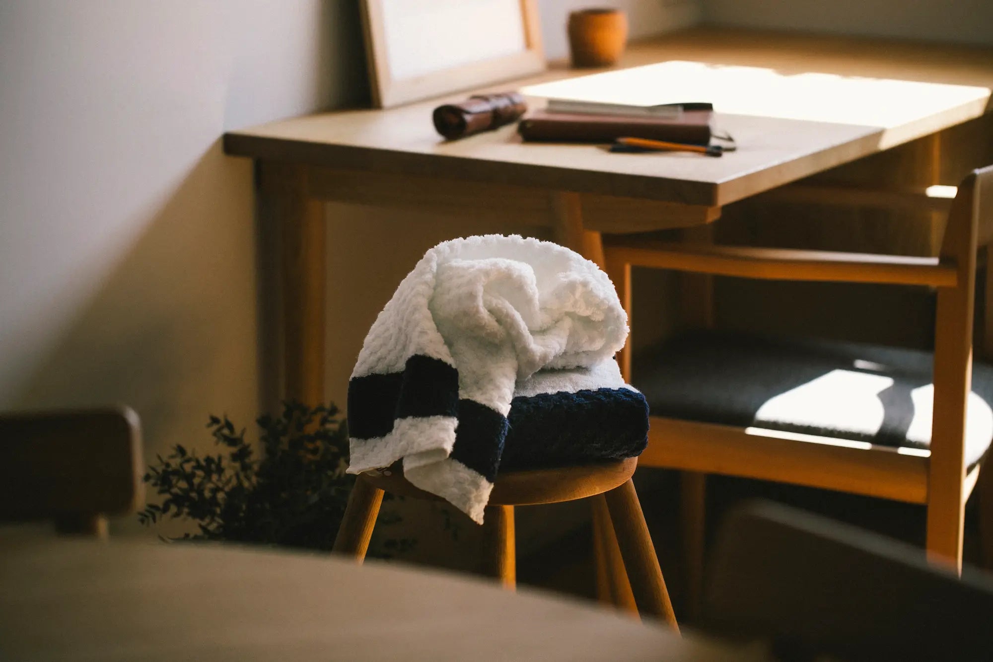 Stack of white with navy line jacquard weave Imabari towel on a wood chair.